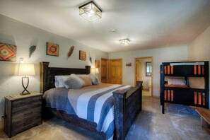 A bedroom with a large bed, bedside tables, a wardrobe, and a ceiling light fixture. - Eagle Pine Lodge - Dog-Friendly Home w/ Pool Access (Custer)