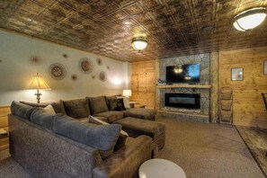 Ein gemütliches Wohnzimmer mit einem Ecksofa, einem Kamin und einem Fernseher.