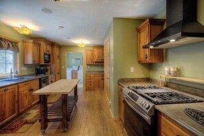 A kitchen with wooden cabinets, a gas stove, and a microwave. - Eagle Pine Lodge - Dog-Friendly Home w/ Pool Access (Custer)
