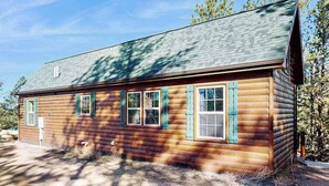 A log cabin with a sloped roof, multiple windows with shutters, and a clear sky. - Meandering Moose Cabin - Secluded Wood Cabin w/ Big Deck (Florissant)