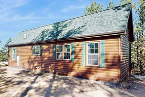 A log cabin with a sloped roof, multiple windows with shutters, and a clear sky. - Meandering Moose Cabin - Secluded Wood Cabin w/ Big Deck (Florissant)