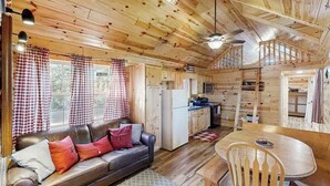 A cabin interior with a sofa, dining table, and kitchen area. - Meandering Moose Cabin - Secluded Wood Cabin w/ Big Deck (Florissant)