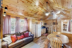 A cabin interior with a sofa, dining table, and kitchen area. - Meandering Moose Cabin - Secluded Wood Cabin w/ Big Deck (Florissant)