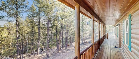 A wooden porch with a view of a forest.