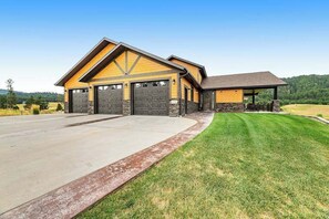A two-story house with a garage, a covered porch, and a well-maintained lawn. - Cedar Lodge on 17- Hot Tub Home Near Mt Rushmore (Sturgis)