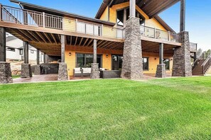 Een huis met twee verdiepingen, een overdekte patio, stenen zuilen en een trap naar de bovenverdieping.