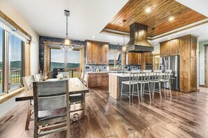 Eine moderne Küche mit Holzschränken, einer zentralen Kochinsel mit Barhocker und großen Fenstern mit Blick.