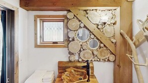 A bathroom with a wooden sink, a window with bars, and a wall decorated with wooden discs and mirrors. - Treehouse Retreat • Pikes Peak Views with Hot Tub (Florissant)