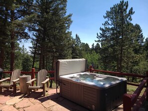 Ein Whirlpool mit einer Holterrasse, umgeben von einem roten Geländer, eingebettet in einen bewaldeten Bereich.