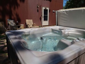 A hot tub with a wooden deck and a door in the background. - Treehouse Retreat • Pikes Peak Views with Hot Tub (Florissant)