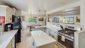 Eine moderne Küche mit weißen Schränken, einer Mittelinsel, einem eingebauten Backofen und einem Kühlschrank.