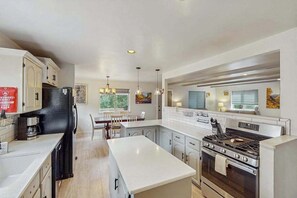 Eine moderne Küche mit weißen Schränken, einer Mittelinsel, einem eingebauten Backofen und einem Kühlschrank.