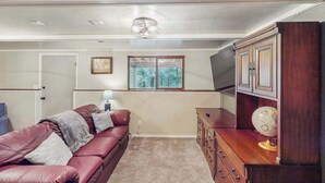 Ein Wohnzimmer mit einem roten Ledersofa, einem Holzschrank und einem Globus darauf.