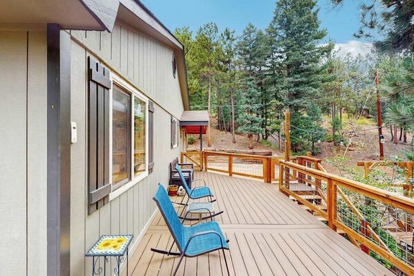 Une terrasse en bois avec des sièges extérieurs et une vue sur une zone boisée.