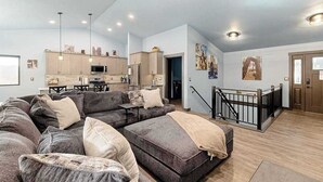 En moderne stue med en hjørnesofa, et spiseområde og et køkken.