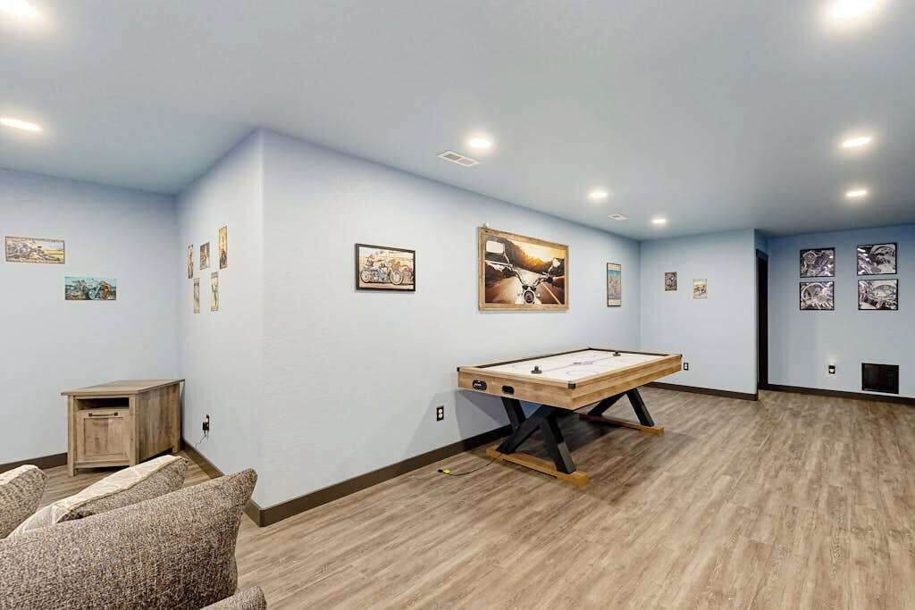 Una habitación con mesa de billar, cuadros en las paredes y un mueble pequeño.