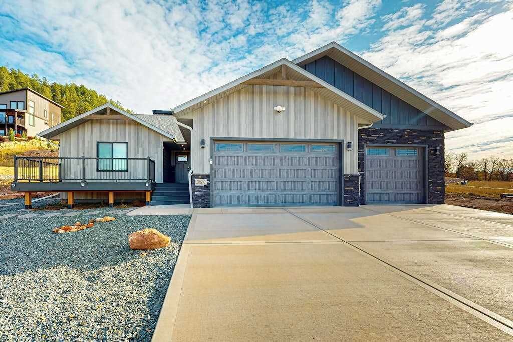 Una moderna casa a due piani con garage, balcone e vialetto.
