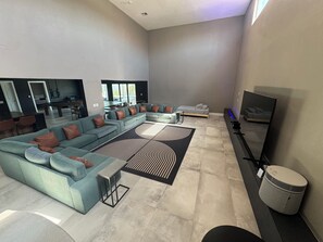 Ein modernes Wohnzimmer mit einem Ecksofa, einem Flachbildfernseher und einem gemusterten Teppich.