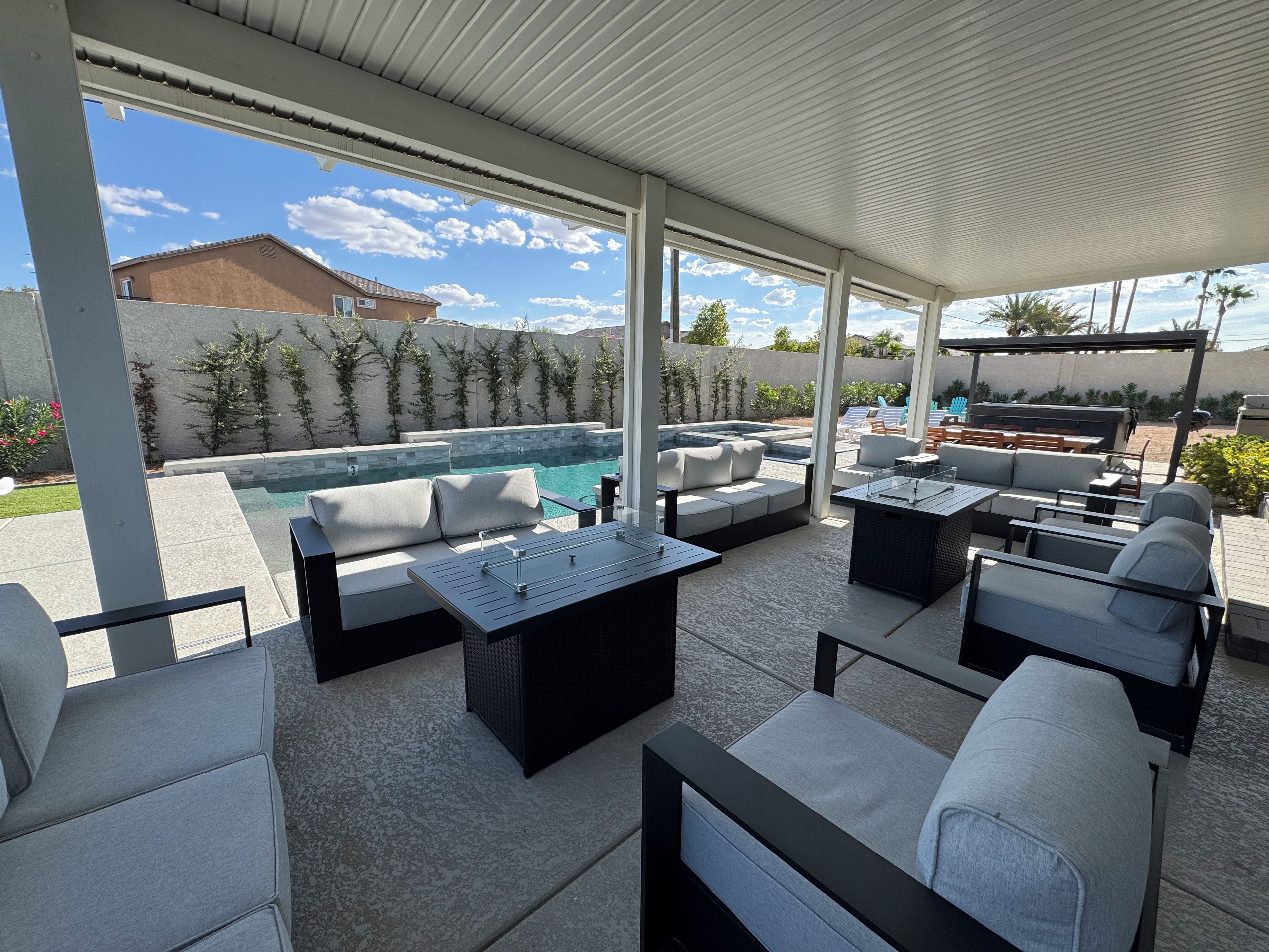 An outdoor patio with a pool, seating areas, and a pergola structure.