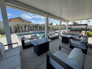 En uteplats med pool, sittplatser och en pergola.