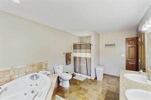 A bathroom with a bathtub, toilet, and sink. - Stratobowl Escape - Dual-Unit Home Near Black Hills Fun (Rapid City)