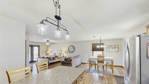 A kitchen with a granite countertop, wooden chairs, a stainless steel refrigerator, and pendant lighting. - Stratobowl Escape - Dual-Unit Home Near Black Hills Fun (Rapid City)