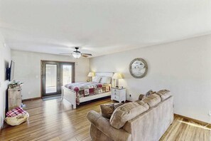 A bedroom with a bed, bedside tables, a ceiling fan, and a wall clock. - Stratobowl Escape - Dual-Unit Home Near Black Hills Fun (Rapid City)