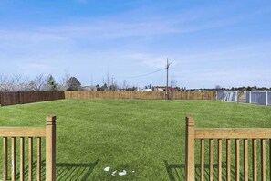Ein umzäunter Garten mit Holztür, blauem Himmel und Holzlattenzaun.