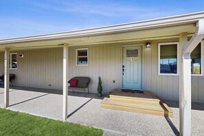 A single-story building with a covered porch, a front door, and a small seating area with a bench and a potted plant. - Stratobowl Escape - Dual-Unit Home Near Black Hills Fun (Rapid City)