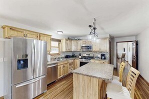 Eine moderne Küche mit Edelstahlgeräten, Holzschränken und einer zentralen Kochinsel mit Sitzgelegenheiten.
