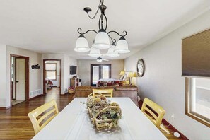 A dining area with a white table, yellow chairs, a chandelier, and a decorative centerpiece. - Stratobowl Escape - Dual-Unit Home Near Black Hills Fun (Rapid City)