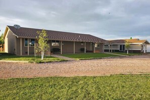 A single-story building with a flat roof, a covered porch, and a gravel driveway. - Stratobowl Escape - Dual-Unit Home Near Black Hills Fun (Rapid City)
