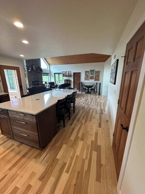 A spacious kitchen with a large island, wooden flooring, and a stone accent wall. - Aces and Eights Lodge (Sturgis)