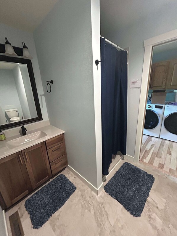 A bathroom with a sink, mirror, and wooden cabinets. - Aces and Eights Lodge (Sturgis)