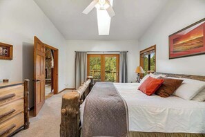 A bedroom with a bed, a window, a door, and a ceiling fan. - Aces and Eights Lodge (Sturgis)