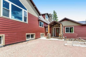 A two-story building with a red exterior, a stone entrance, and a gravel driveway.