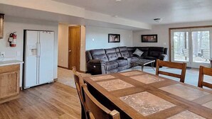 A spacious living area with a dining table, a sofa, and a kitchen area with a refrigerator. - Boxelder Bluff - Secluded Home • Mountain Views (Rapid City)