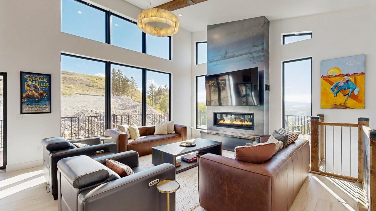 Un salon spacieux doté d’une cheminée, de grandes fenêtres et d’un balcon.