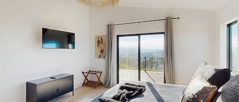 Un dormitorio moderno con una cama grande, un televisor de pantalla plana, un balcón con vistas y un techo de madera.