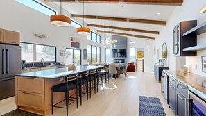 Een moderne keuken met een centraal eiland, barkrukken en een eethoek met een televisie.