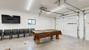 Ein Konferenzraum mit einem langen Tisch, Stühlen, einem Flachbildfernseher und einem Fenster.