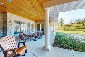 Eine Terrasse im Freien mit Holzboden, einem Tisch mit Stühlen und Blick auf eine grüne Landschaft.