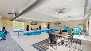 Ein Poolhaus mit Pool, Stühlen und einem Tisch.