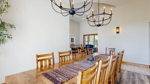 Ein Essbereich mit Holztisch, Stühlen, einer Chandelier und Blick auf einen Balkon.