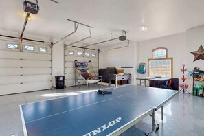 A ping pong table in a garage with a projector and a folding chair.