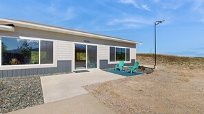 A modern building with large windows, a covered patio with chairs, and a gravel driveway. - High Country Pool House - Private Indoor Pool • 2 Hot Tubs (Sturgis)