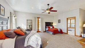A bedroom with two beds, a ceiling fan, and a large window. - High Country Pool House - Private Indoor Pool • 2 Hot Tubs (Sturgis)