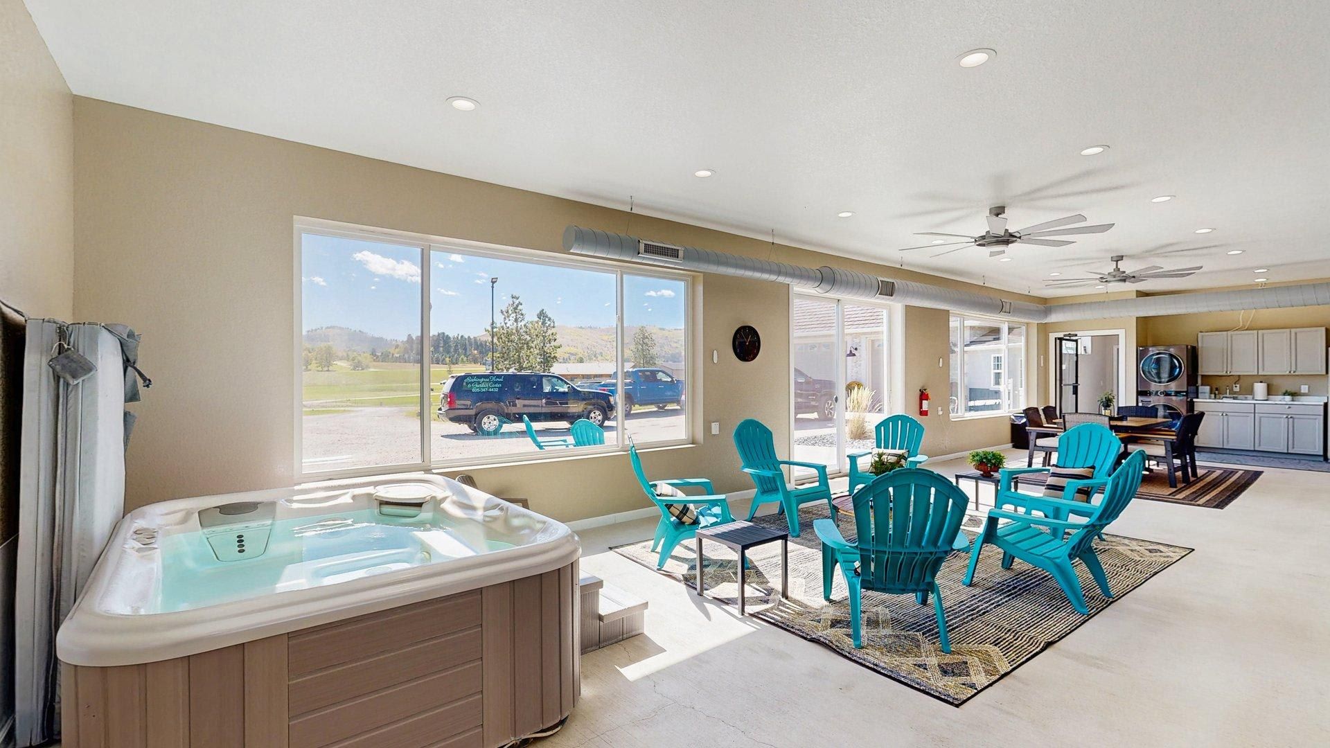 A spacious room with a hot tub, large windows, and a ceiling fan.