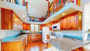A spacious kitchen with wooden cabinets, a central island, and a microwave. - Hilltop Getaway - Hilltop Home • Hot Tub & Billiards (Lead)