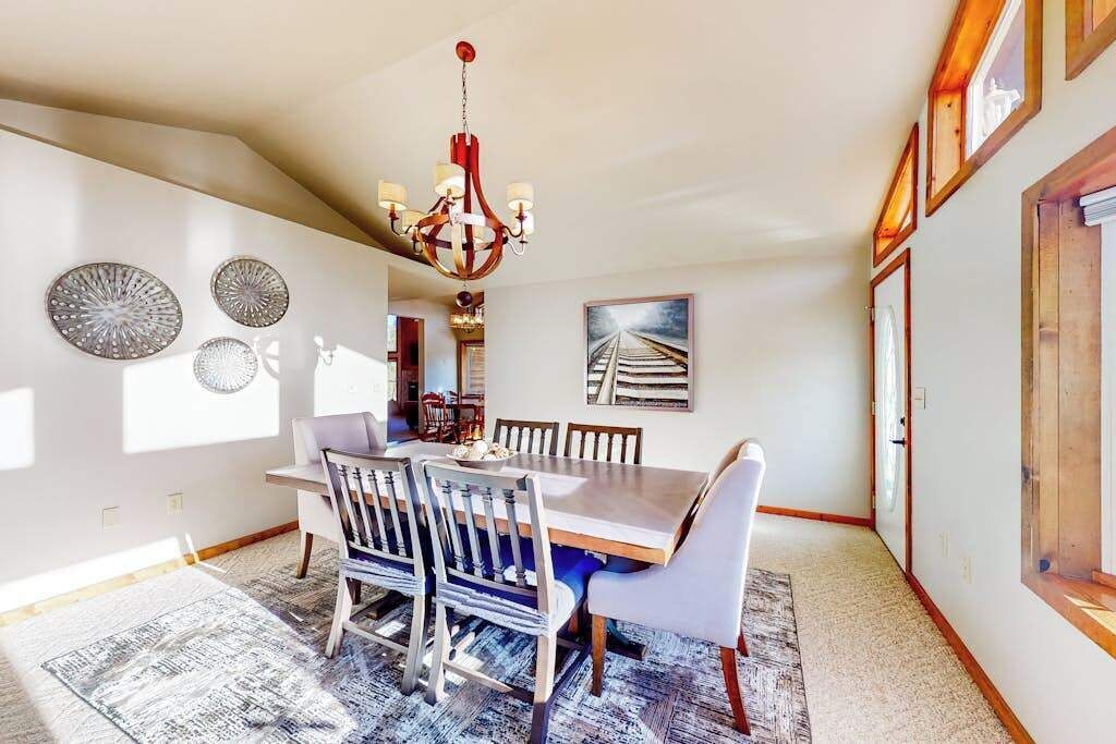 A dining area with a wooden table, chairs, a chandelier, and wall decor.